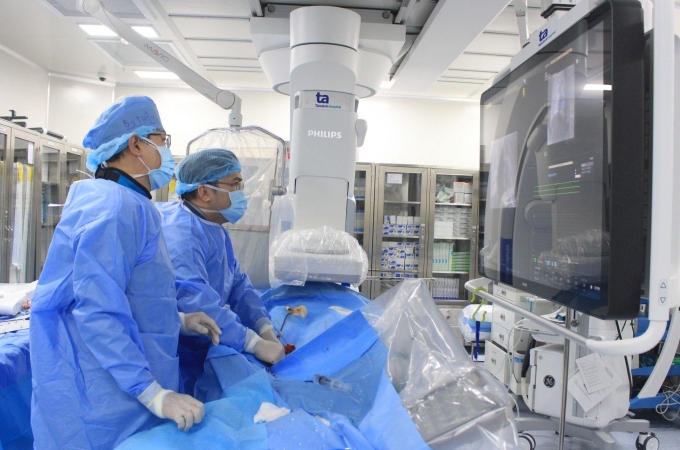 BS.CKI Vũ Năng Phúc (thứ 2 từ trái sang) và BS.CKI Lương Minh Thông thực hiện thủ thuật đóng lỗ thông trong tim cho bệnh nhân. Ảnh: Bệnh viện Tâm Anh