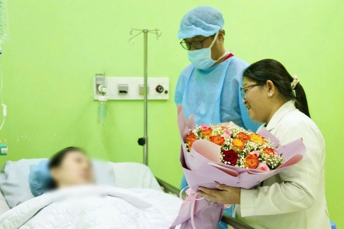 Bác sĩ Trịnh Nhựt Thư Hương, Trưởng Khoa Chăm sóc trước sinh, Bệnh viện Từ Dũ, thành viên kíp can thiệp, tặng hoa chúc mừng thai phụ và chồng (đứng bên cạnh) sau ca can thiệp thành công. Ảnh: Bệnh viện cung cấp