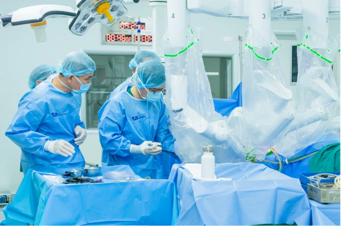 Bác sĩ Minh Hùng (trái) điều khiển cánh tay robot từ xa, cắt khối u trực tràng cho bà Thu. Ảnh: Bệnh viện Đa khoa Tâm Anh