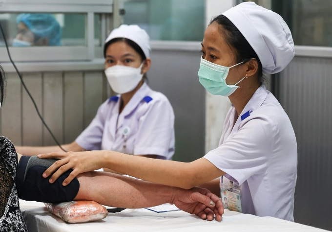 Nhân viên y tế đo huyết áp cho bệnh nhân. Ảnh: Quỳnh Trần