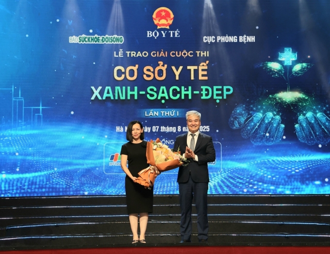 Ông Trần Tuấn Linh, Tổng biên tập báo Sức khỏe và Đời sống tặng hoa bà Nguyễn Bạch Điệp. Với vai trò nhà tài trợ, hệ thống nhà thuốc và tiêm chủng Long Châu mong góp một phần nhỏ lan tỏa tinh thần xanh - sạch - đẹp đến tất cả đơn vị trong ngành y tế. Ảnh: LC