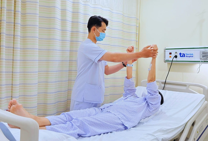 Kỹ thuật viên hỗ trợ bà Sáu các bài tập vận động nhẹ tại giường. Ảnh: Bệnh viện Đa khoa Tâm Anh