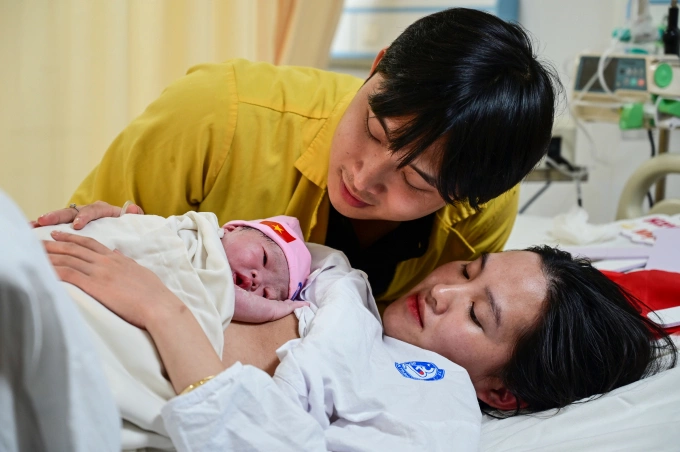 Vợ chồng chị Kim Anh bên cạnh con gái đầu lòng. Ảnh: Giang Huy