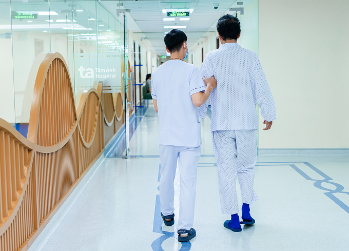 Kỹ thuật viên hướng dẫn anh Nguyên tập phục hồi chức năng sau ca phẫu thuật. Ảnh: Bệnh viện Đa khoa Tâm Anh