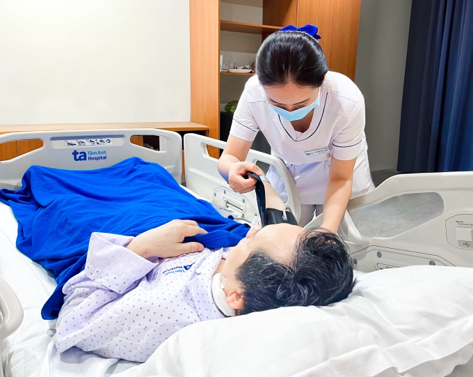 Điều dưỡng kiểm tra huyết áp cho anh David trước lúc xuất viện. Ảnh: Hạ Vũ