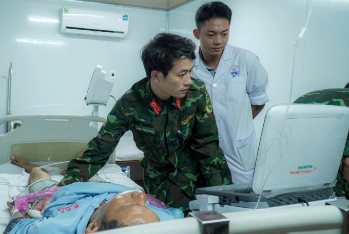 Trung tá, bác sĩ Phạm Trường Thanh đánh giá sức khỏe bệnh nhân trước khi đưa lên trực thăng. Ảnh: Bệnh viện cung cấp