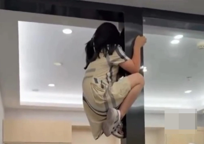 Bé gái leo lên khung cửa phòng khám vì sợ điều trị răng. Ảnh chụp màn hình