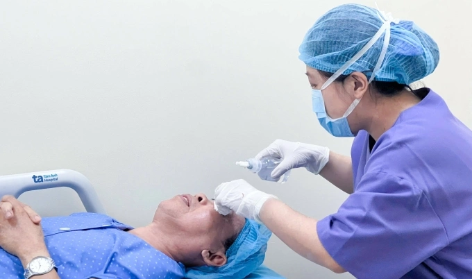 Nhân viên y tế nhỏ thuốc rửa mắt, sát trùng vùng mắt cho ông Thanh trước phẫu thuật. Ảnh: Bệnh viện Đa khoa Tâm Anh
