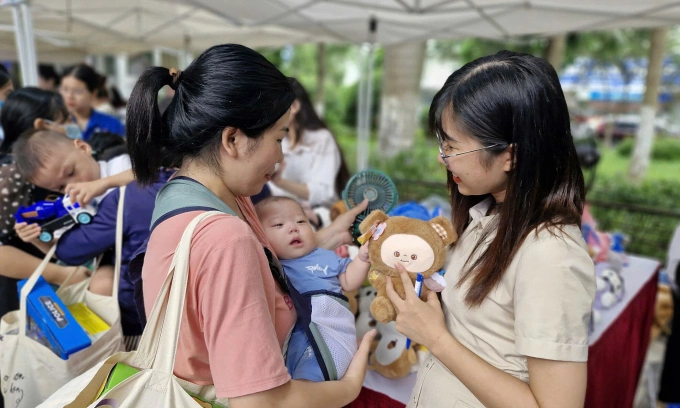 Cha mẹ bế em bé tham gia hội chợ miễn phí tại bệnh viện. Ảnh: Lê Nga