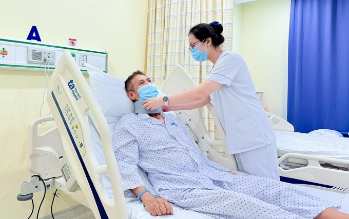 Điều dưỡng điều chỉnh nẹp cổ cho ông Viễn sau phẫu thuật. Ảnh: Bệnh viện Đa khoa Tâm Anh