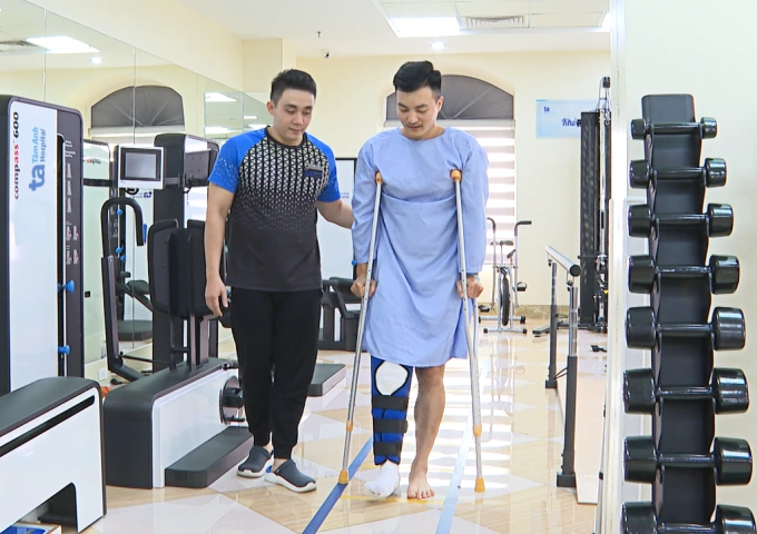 Chuyên viên phục hồi chức năng hướng dẫn anh Huy đi lại bằng nạng. Ảnh: Bệnh viện Đa khoa Tâm Anh