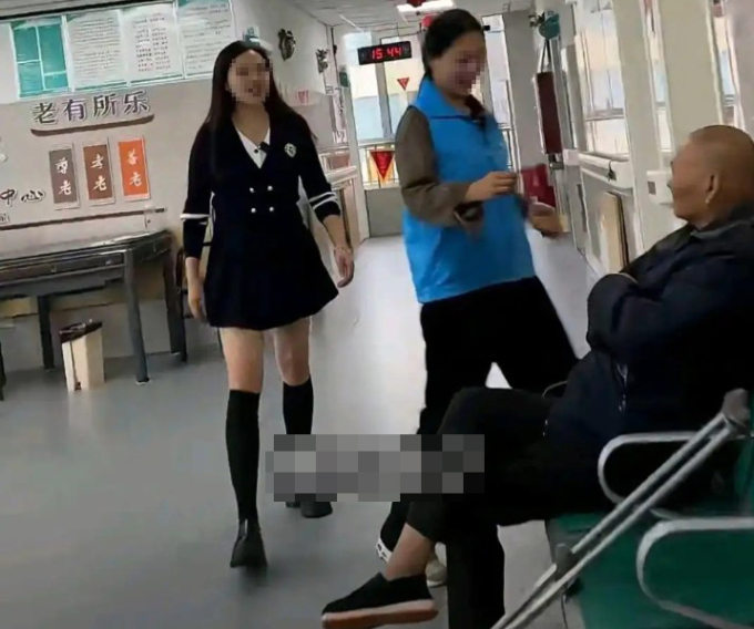 Trong video, nhân viên mặc váy nhảy, người còn lại cho các cụ uống thuốc. Ảnh chụp màn hình