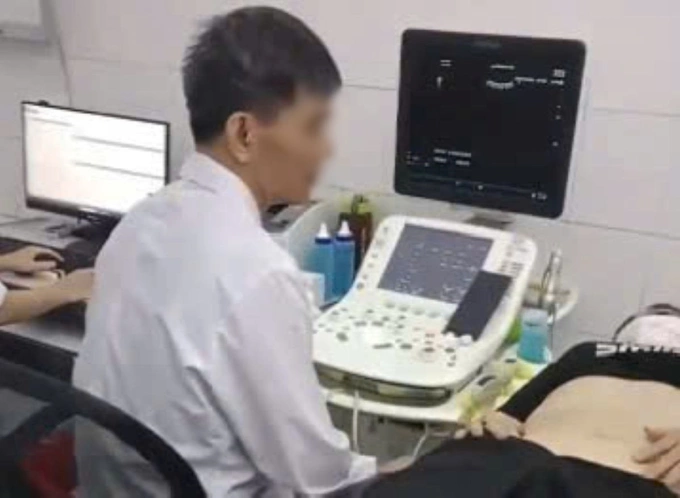 Bác sĩ Bệnh viện Đa khoa Thường Xuân bị phản ứng vì vừa siêu âm vừa xem bóng đá trên điện thoại. Ảnh cắt từ clip