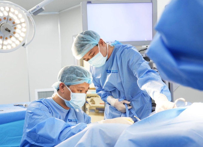 Bác sĩ Quang Nhật (trái) phẫu thuật khoét chóp cổ tử cung điều trị tổn thương tiền ung thư phụ khoa. Ảnh: Tuệ Diễm.