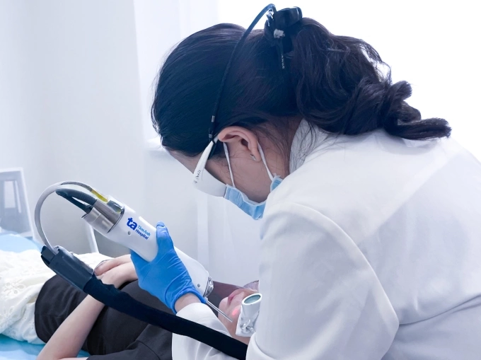 Bác sĩ Trang sử dụng laser Nd:YAG xung dài giảm mụn viêm và hồng ban sau mụn cho chị Hằng. Ảnh: Bệnh viện Đa khoa Tâm Anh
