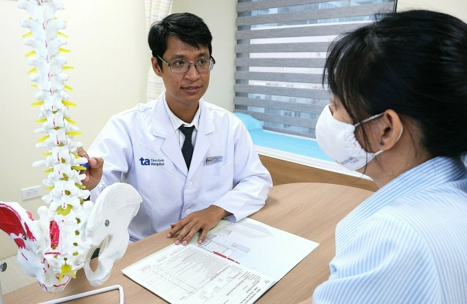 Bác sĩ Duận giải thích tình trạng cột sống cho người bệnh. Ảnh: Bệnh viện Đa khoa Tâm Anh