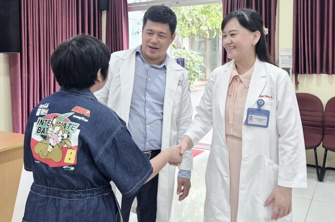 Hai bé gái cao thêm 10 cm sau ca mổ nắn cột sống Bé Lâm trò chuyện cùng bác sĩ Đặng Khải Minh và Phan Huỳnh Bảo Nghi, ngày 2/12. Ảnh: Lê Phương