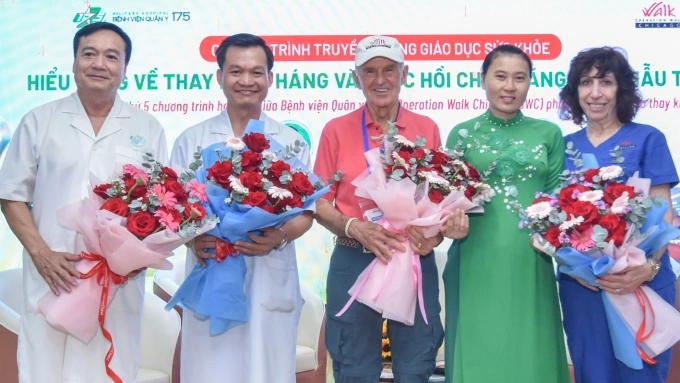 Chị Liễu (áo dài xanh) tặng hoa cảm ơn bác sĩ Bệnh viện Quân y 175 và Tổ chức Operation Walk Chicago (Mỹ), chiều 13/4. Ảnh: Thanh Thủy