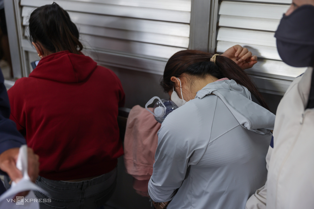 An exhausted patient falls asleep in a crowded waiting hall.